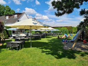 einen Park mit Rutsche, Tischen und Sonnenschirmen in der Unterkunft Hotel Am Wintergarten in Bocholt