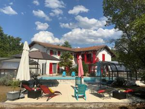 Commensacq的住宿－杜曼德拉貝魯住宿加早餐旅館，房屋前的带椅子和遮阳伞的游泳池