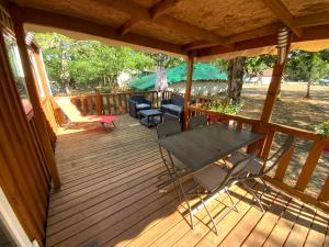 a wooden deck with chairs and a table on it at Maison d'Hôtes Domaine de Labelo in Commensacq