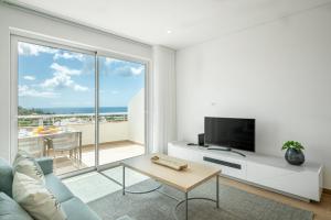 ein Wohnzimmer mit einem Sofa, einem TV und einem Balkon in der Unterkunft Green Beach Ocean View - Porto de Mos in Lagos
