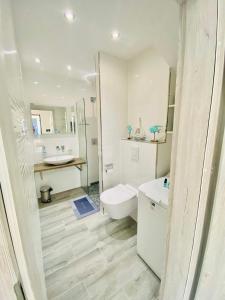 a white bathroom with a toilet and a sink at "Blue Sun" Apartament 11B HorizonPark Dziwnòwek in Dziwnówek