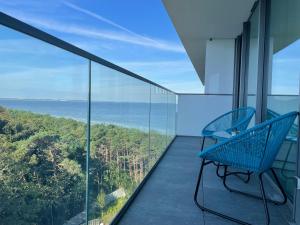 a blue bench on a balcony with a view of the ocean at Wave by Baltic Home in Międzyzdroje