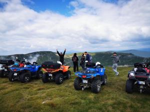 a group of people standing on top of a hill with atvs at Pensiunea Valea Șușiței, Ciubar, Sauna, ATV, Safarii Jepp Offroad Ghid Turistic, Climbing, Rafting, Paragliding in Târgu Jiu