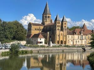 un grande edificio con una chiesa accanto a un corpo d'acqua di Les Logis de Paray Appartement 201 a Paray-le-Monial