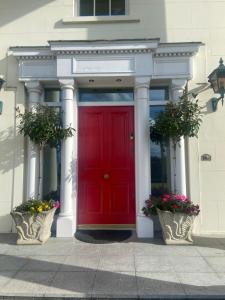 a red door on a building with two potted plants at Redgate House Bed & Breakfast in Derry Londonderry