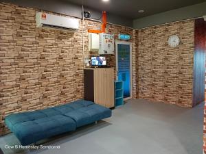 Una habitación con un sofá azul frente a una pared de ladrillos. en Cow B Homestay Semporna, en Semporna