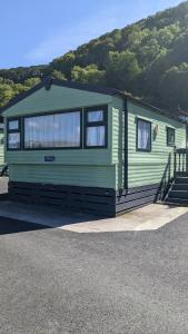 une remorque verte garée devant une montagne dans l'établissement Gloria Stay - Aberystwyth Caravan, à Aberystwyth