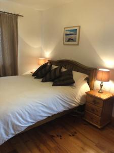 a bedroom with a bed with pillows and a night stand at Luxury Sea View Cottage Ballyconneely Winter Specials in Ballyconneely