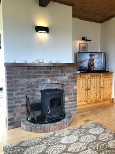 a brick fireplace in a living room with a tv at Luxury Sea View Cottage Ballyconneely Winter Specials in Ballyconneely