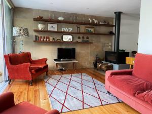 a living room with two red couches and a tv at Casa das Boganvilias - Moradia com jardim in Lisbon