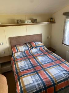 a bedroom with a bed with a plaid blanket at Thornwick Bay Haven Site-Large Homely Static Caravan, Sun, Sea And Sand (SEA VEIWS , LIGHTHOUSE VEIWS) in Flamborough