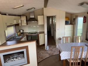 a kitchen and dining room with a table and a fireplace at Thornwick Bay Haven Site-Large Homely Static Caravan, Sun, Sea And Sand (SEA VEIWS , LIGHTHOUSE VEIWS) in Flamborough