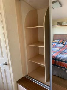 a closet with wooden shelves and a bed at Thornwick Bay Haven Site-Large Homely Static Caravan, Sun, Sea And Sand (SEA VEIWS , LIGHTHOUSE VEIWS) in Flamborough