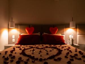 uma cama com corações nas almofadas com pássaros em Alameda Alegra Hotel em Gramado