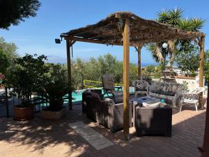 a pergola with couches and chairs on a patio at Villetta dei Tramonti in Trappeto