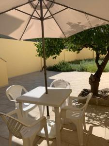 uma mesa branca e cadeiras com um guarda-sol em Toto House em Mesagne