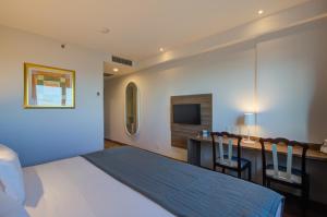 a bedroom with a bed and a desk with a television at Bourbon Cambará Hotel in Cambará