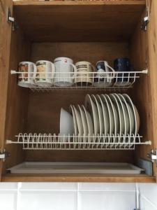 a cupboard with plates and mugs in it at Apartment Na Lidzava Beach in Pizunda