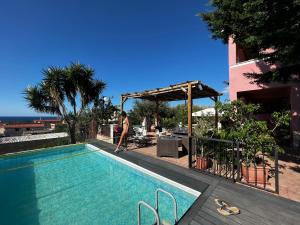 una donna è in piedi accanto a una piscina di Villetta dei Tramonti a Trappeto