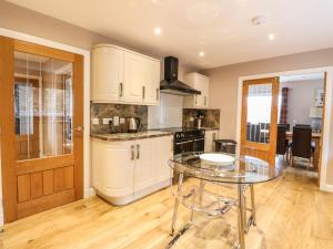 a kitchen with white cabinets and a glass table at Luxury Highland Home in Scotlands' Great Glen in Gairlochy