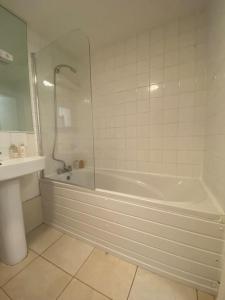 a white bathroom with a tub and a sink at Comfy 2 bed Flat with free Parking, close to Tube in Woolwich