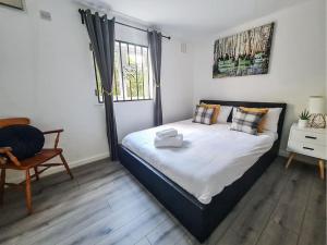 a bedroom with a bed and a chair and a window at Comfy 2 bed Flat with free Parking, close to Tube in Woolwich