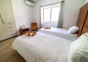 a bedroom with two beds and a window at Cancun Airport Condo Hotel Apartment with pool and security in Cancún