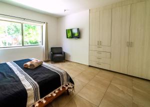1 dormitorio con 1 cama, 1 silla y TV en Cancun Airport Condo Hotel Apartment with pool and security, en Cancún
