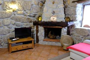 セロリコ・デ・バストにあるCasa de Pedraの石壁のリビングルーム(テレビ、暖炉付)
