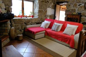 セロリコ・デ・バストにあるCasa de Pedraの石壁の部屋の赤いソファ
