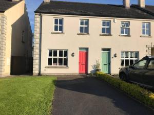 a white house with a red door and a car parked in front at Modern 3-bedroom townhouse in the Mournes in Newry