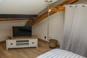 a bedroom with a bed and a tv on a cabinet at CROIX BLANCHE - LE LOGIS in Tournan-en-Brie
