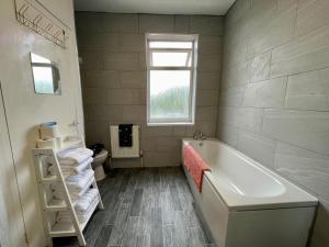 a bathroom with a tub and a toilet and a window at Kimberworth House, 4 Bedrooms, WIFI, Close to M1, Longer Stay, Free Parking in Rotherham