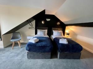 a bedroom with two beds with blue blankets and a chair at Kimberworth House, 4 Bedrooms, WIFI, Close to M1, Longer Stay, Free Parking in Rotherham