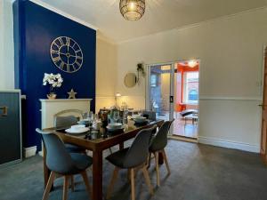 a dining room with a table and chairs and a clock on the wall at Kimberworth House Rotherham, 4 Bedrooms, Close to M1, Longer Stay, Free Parking in Rotherham
