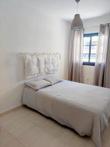 a white bed with white pillows and a window at Casa Cris in La Lajita