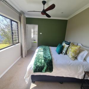 a bedroom with a large bed with a ceiling fan at Luxury Home with breathtaking views of Champagne Valley in Bergview