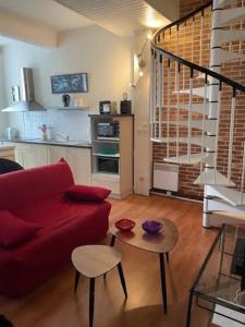 un salon avec un canapé rouge et une table dans l'établissement DUPLEX N°3 AU COEUR DE BAGNERES DE BIGORRE, à Bagnères-de-Bigorre