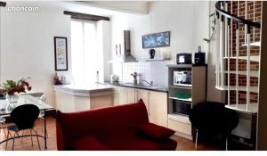un salon avec un canapé rouge et une cuisine dans l'établissement DUPLEX N°3 AU COEUR DE BAGNERES DE BIGORRE, à Bagnères-de-Bigorre