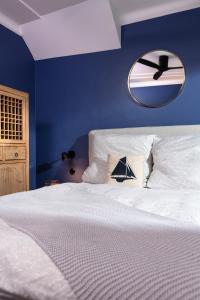 ein blaues Schlafzimmer mit einem weißen Bett und einem Spiegel in der Unterkunft Warnemünde: Apartment KAJÜTE - nur 3 Gehminuten zum Strand in Warnemünde