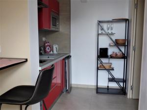 a small kitchen with red cabinets and a black chair at LE SEPT charmant studio aux portes des calanques in Cassis