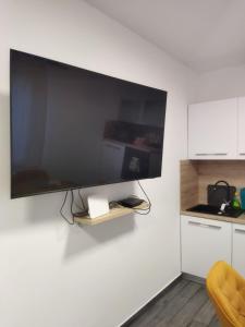 a large flat screen tv on the wall of a kitchen at Apartman na jezeru in Zagreb