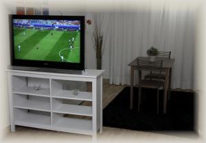 sala de estar con TV en un soporte blanco con mesa en Just House en Campagnano di Roma