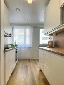 a kitchen with white cabinets and a large window at City Pearl II in Jyväskylä