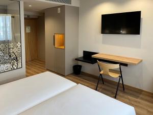 a room with a bed and a desk and a television at room Select Porto in Porto