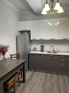 a kitchen with white cabinets and a table and a refrigerator at Dona Palace Gold in Tbilisi City