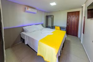 1 dormitorio con 1 cama grande con manta amarilla en Pousada Maanaim Porto en Porto de Galinhas