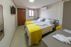 a bedroom with two beds and a yellow blanket at Pousada Maanaim Porto in Porto De Galinhas