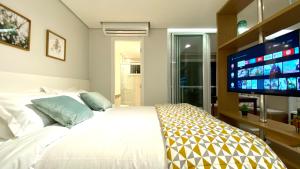 um quarto com uma cama branca e uma televisão de ecrã plano em CPM- Praça MADÁ By Anora Spaces em São Paulo