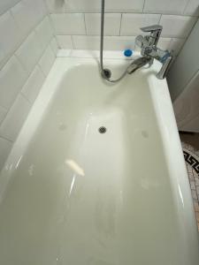een wit bad met een kraan in de badkamer bij iAparts Богенбай батыра-Шагабутдинова in Alma-Ata